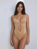 A woman modeling a nude-beige one-piece bodysuit with thin shoulder straps, molded cups, and a central keyhole cutout detail, posed against a light gray studio background.
